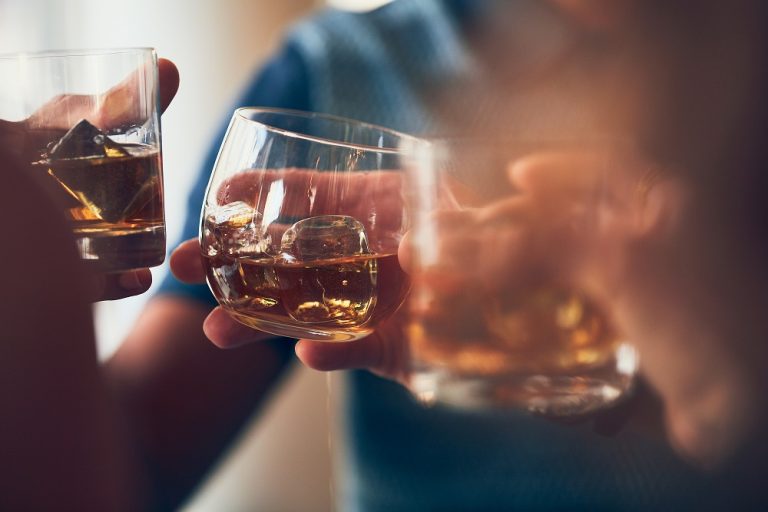 Closeup shot of many people clinking glasses with alcohol at a toast